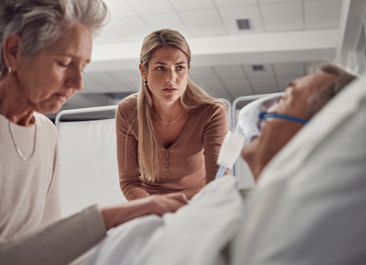 Angehörige begleiten einen schwer erkrankten Menschen am Krankenbett